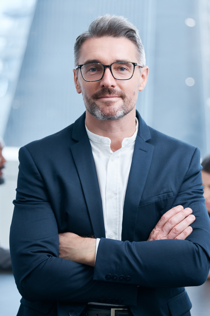 Man standing with arms folded wearing glasses