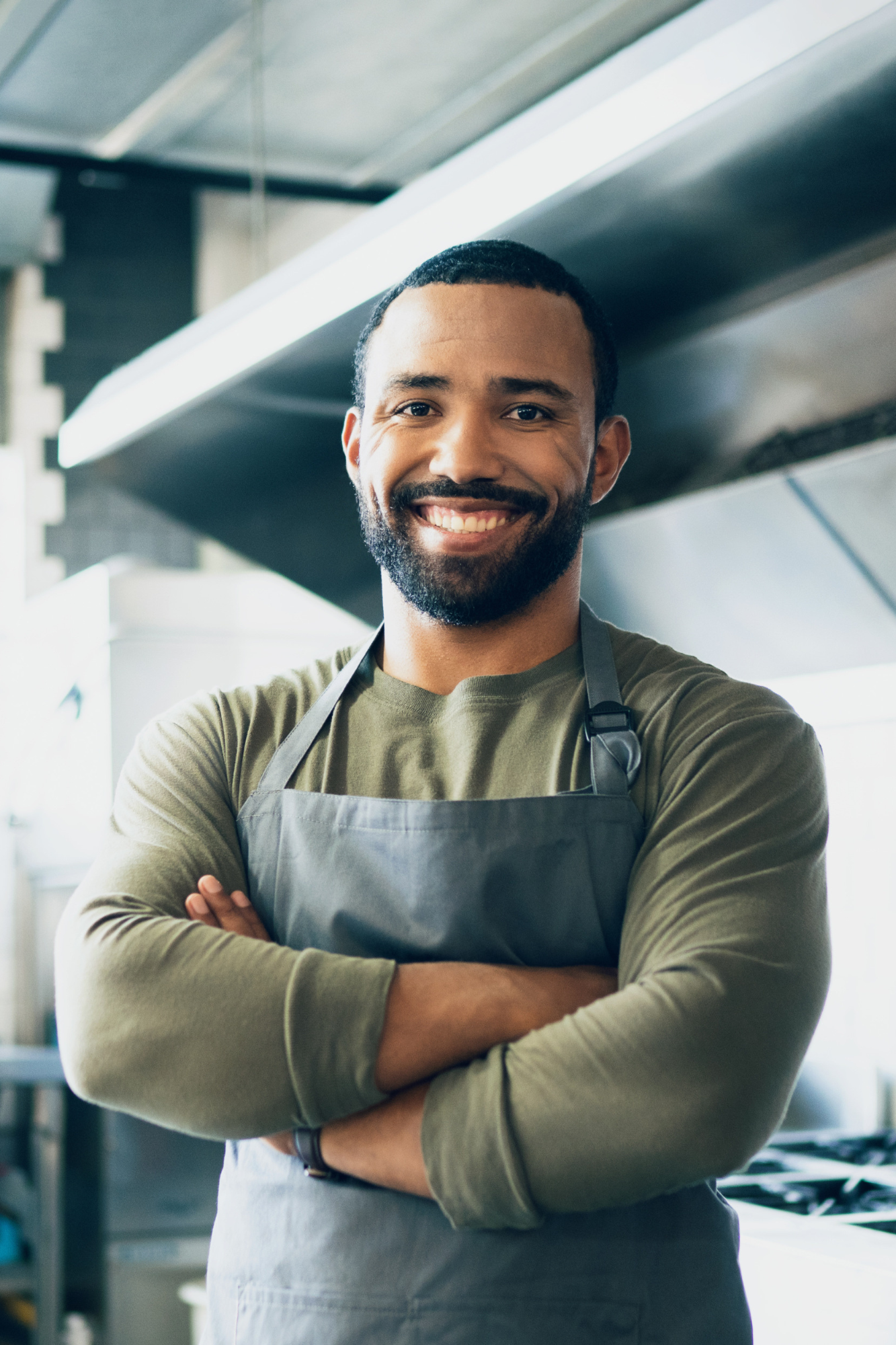 Happy man, chef and small business owner at restaurant for hospitality service, cooking or food in kitchen. Portrait of male person, employee or waiter smile in confidence for professional culinary.